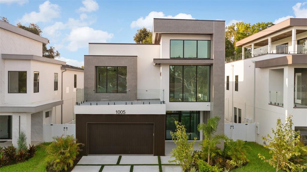 A modern two-story house with a flat roof, gray and white exterior, and glass balconies — 1005 W BRADDOCK STREET, TAMPA, FL