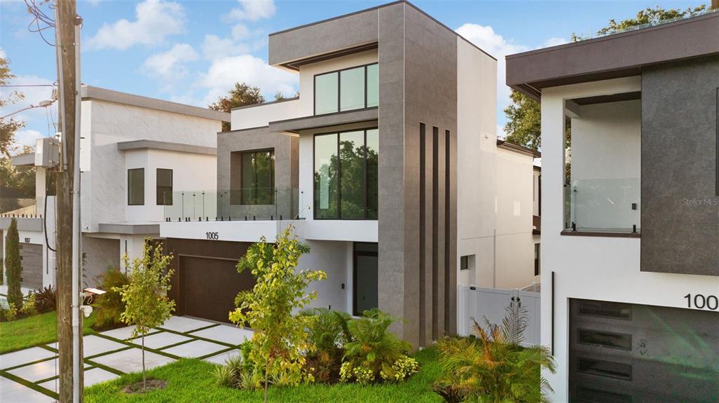 A modern two-story house with a flat roof, glass balcony, and gray stone accents — 1005 W BRADDOCK STREET, TAMPA, FL