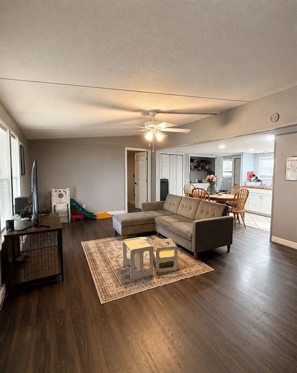 A living room with dark wood floors, a grey sectional sofa, and an open kitchen — 2303 NW 14th Avenue # 534, Boynton Beach FL 33436, BOYNTON BEACH, FL
