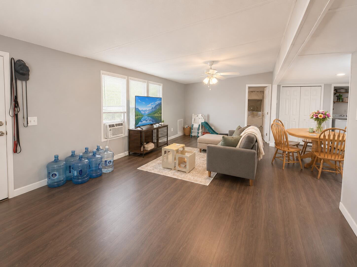 A living room with wood-look flooring, a gray sofa, a television, and a dining area — 2303 NW 14th Avenue # 534, Boynton Beach FL 33436, BOYNTON BEACH, FL