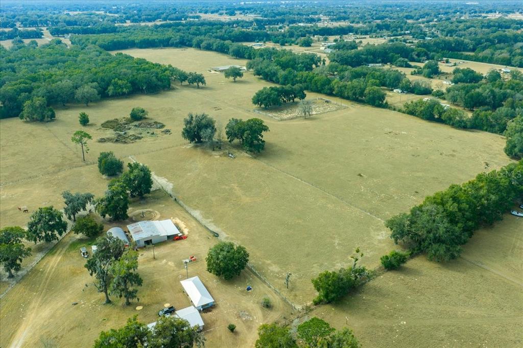 An aerial view shows a large, grassy rural property with several outbuildings and scattered trees — 2051 SE 155TH STREET, SUMMERFIELD, FL
