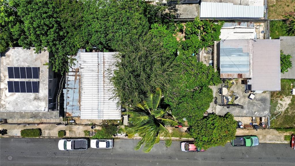 An aerial view shows two adjacent houses with metal roofs and parked cars on the street — 11 ST. EXT. JARDINES DE PALMAREJO, V-20, CANOVANAS, PR
