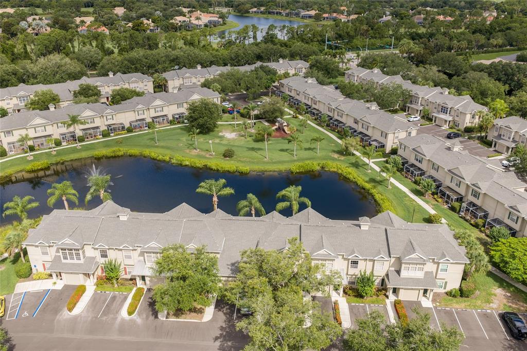An aerial view shows a multi-unit residential complex surrounding a central pond and park — 7633 PLANTATION CIRCLE UNIT 7633, UNIVERSITY PARK, FL