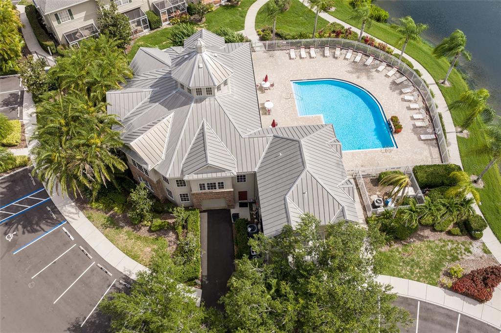 An aerial view of a clubhouse featuring a metal roof, swimming pool, and parking lot — 7633 PLANTATION CIRCLE UNIT 7633, UNIVERSITY PARK, FL