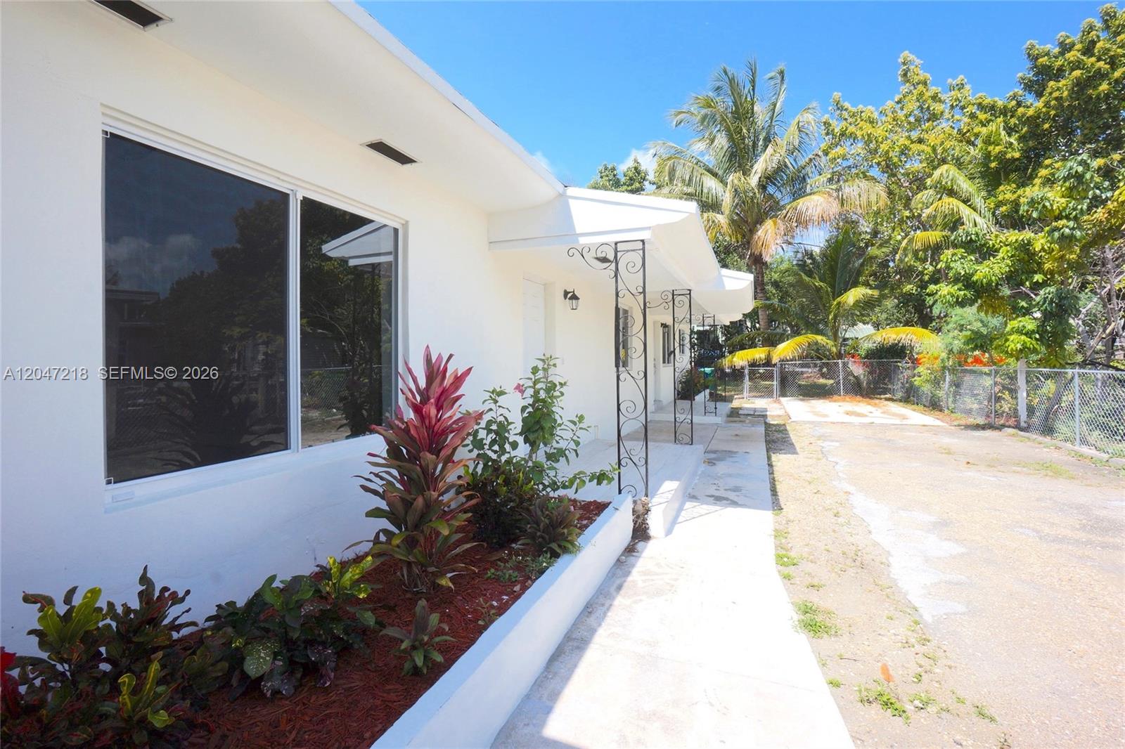 A white house exterior features a concrete walkway, a landscaped planter, and metal porch supports — 1497 NE 118th Ter # 2, Miami FL 33161, MIAMI, FL