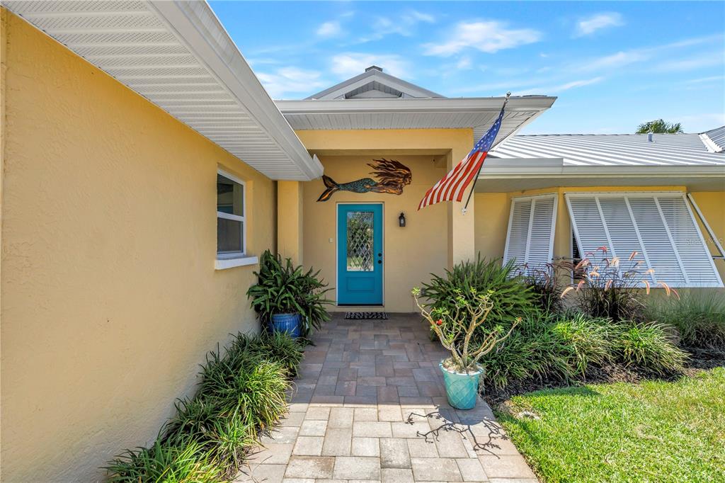 The exterior of a yellow house features a blue front door and a stone walkway — 6113 45TH STREET W, BRADENTON, FL