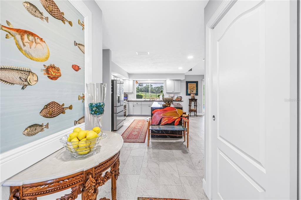 A hallway with a fish-themed wall mural leads into a kitchen with light-colored cabinets — 6113 45TH STREET W, BRADENTON, FL