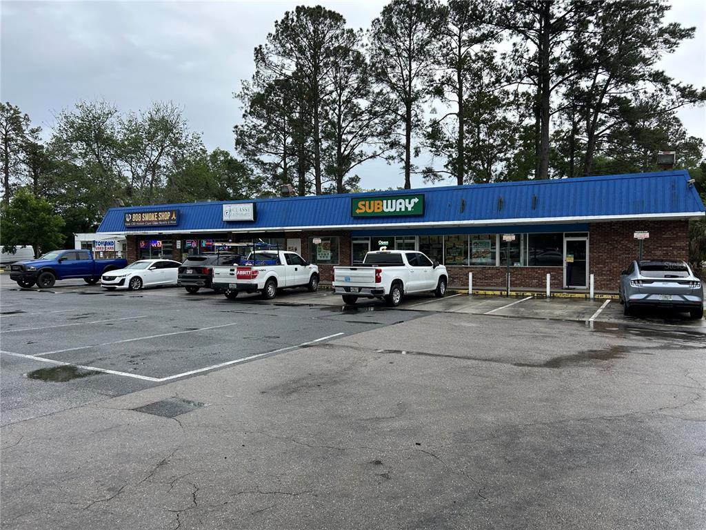A strip mall with a blue metal roof features a Subway and a smoke shop — 203-221 NE 39TH AVENUE, GAINESVILLE, FL