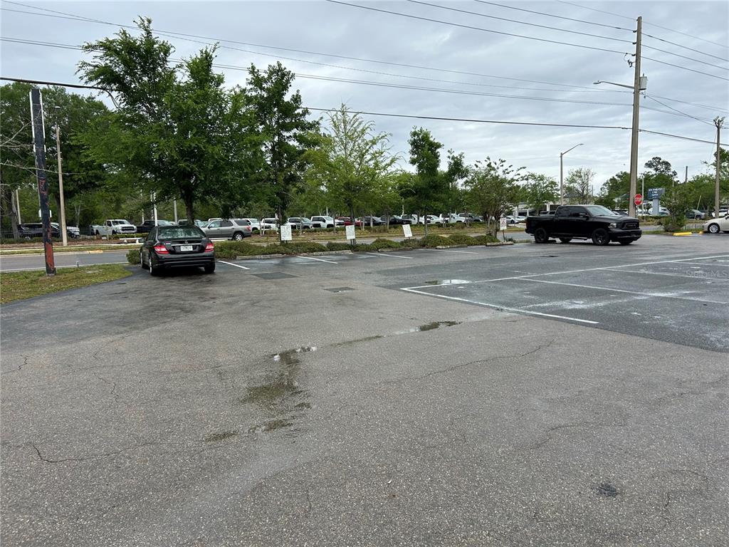 An asphalt parking lot features marked spaces, a black sedan, and a black pickup truck — 203-221 NE 39TH AVENUE, GAINESVILLE, FL