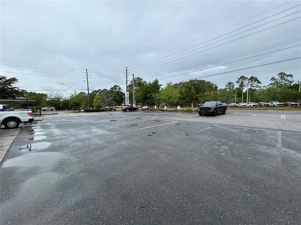 A paved parking lot with a few parked vehicles under a cloudy sky — 203-221 NE 39TH AVENUE, GAINESVILLE, FL