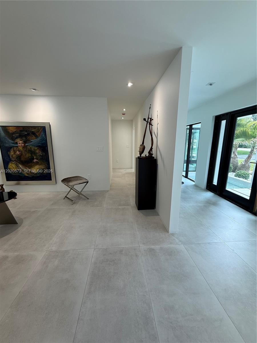 A minimalist entryway features large-format light gray floor tiles, white walls, and a modern sculpture — 439 Hardee Rd, Coral Gables FL 33146, CORAL GABLES, FL