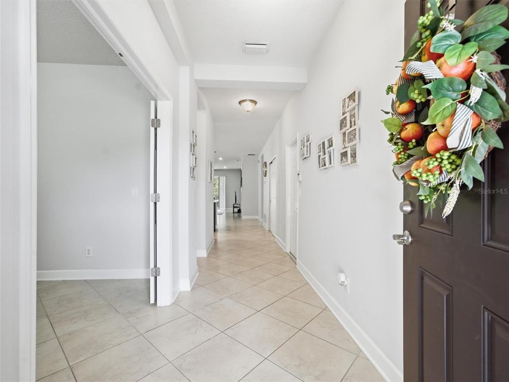 A bright entryway leads into a long hallway with light-colored tile flooring and white walls — 21613 SOUTHERN CHARM DRIVE UNIT DR, LAND O LAKES, FL