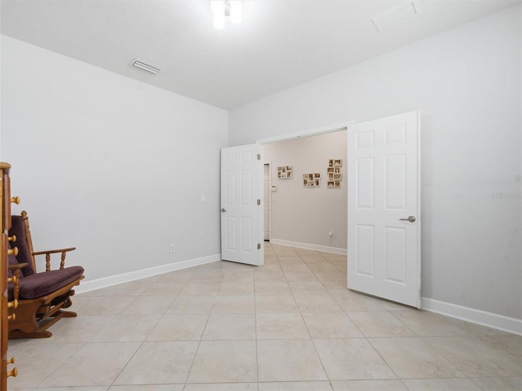 A room with light-colored tile flooring, white walls, and double doors leading to another area — 21613 SOUTHERN CHARM DRIVE UNIT DR, LAND O LAKES, FL