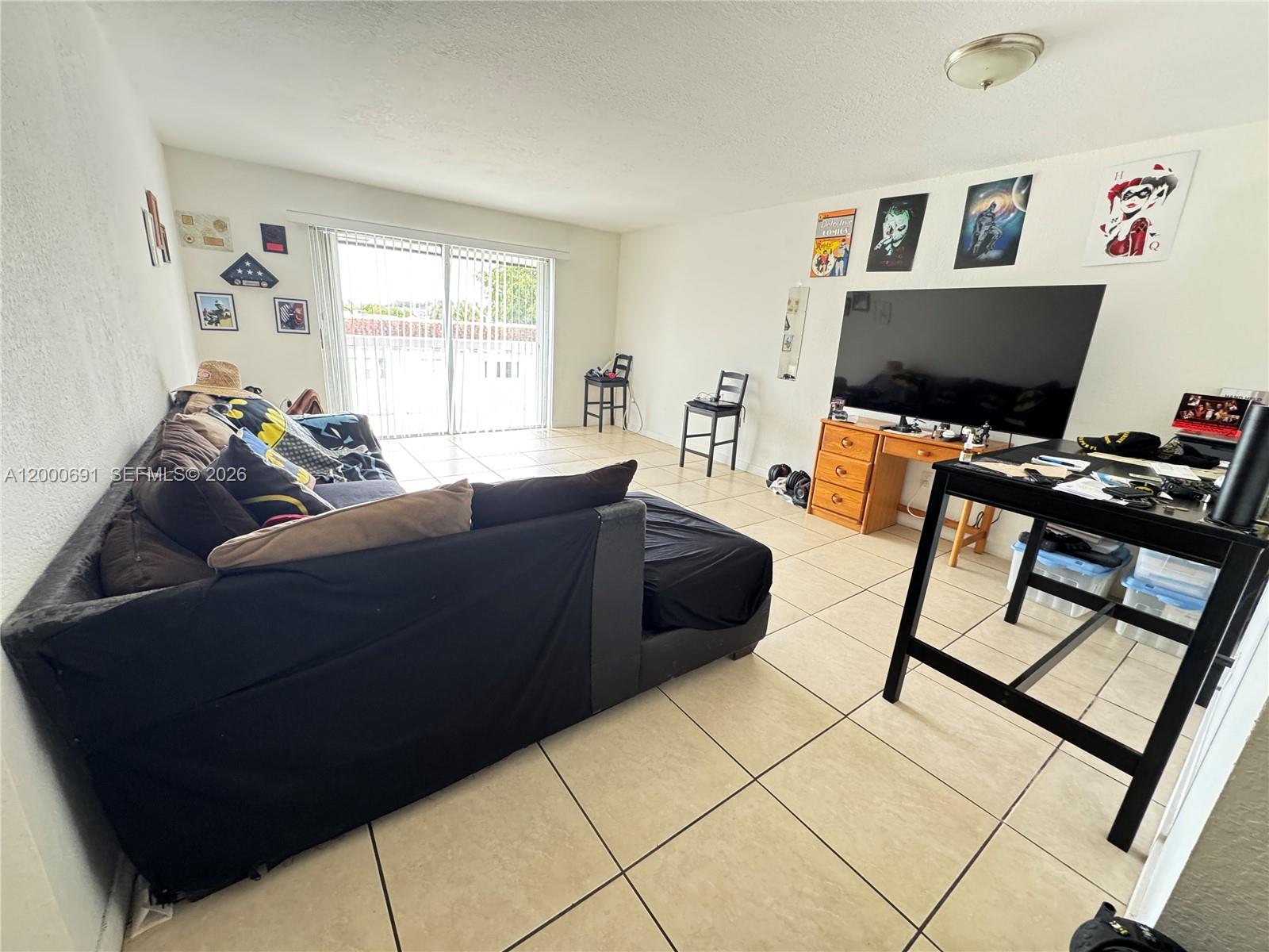 A living room features tile flooring, a large sectional sofa, a television, and sliding glass doors — 15201 NE 6th Ave # C304, Miami FL 33162, MIAMI, FL