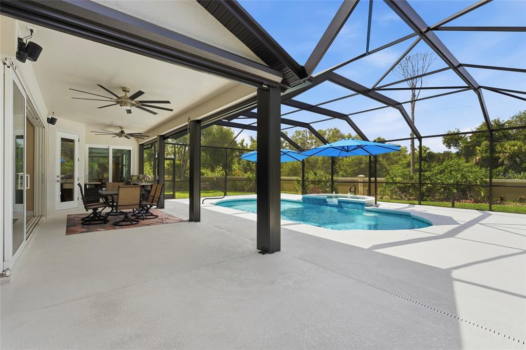 A covered patio with a dining set overlooks a screened-in swimming pool and spa — 6312 TURNERS GAP ROAD, BRADENTON, FL