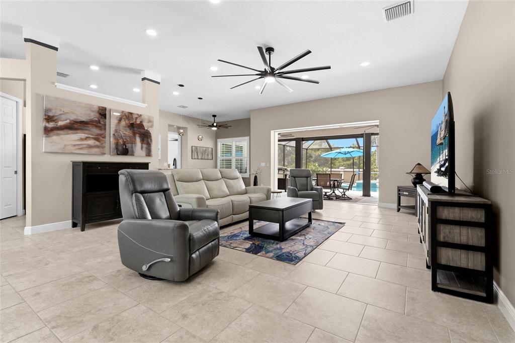 A living room features tile flooring, a large ceiling fan, and sliding doors to a pool — 6312 TURNERS GAP ROAD, BRADENTON, FL