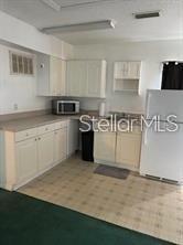 A kitchen features white cabinets, a microwave, a refrigerator, and light-colored vinyl flooring — 804 WASHINGTON PALM LOOP UNIT 5, DAVENPORT, FL