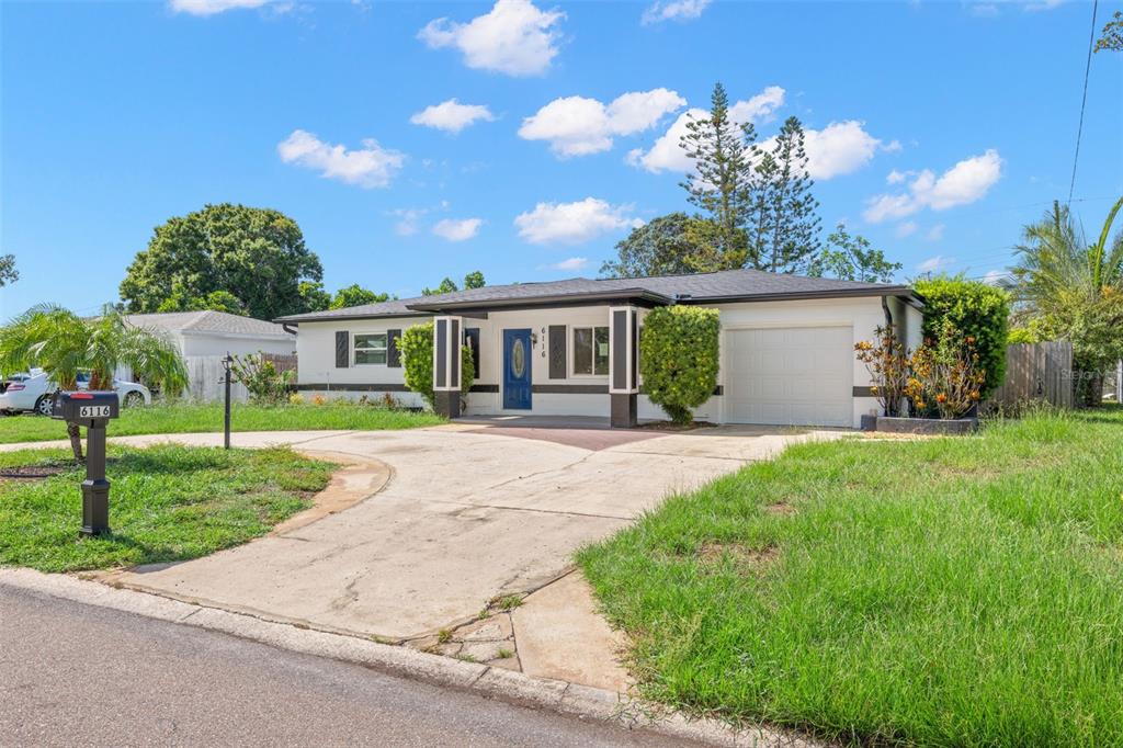 An open-concept kitchen and living area features white cabinetry, stainless steel appliances, and wood-look flooring — 6116 52ND AVENUE N, KENNETH CITY, FL