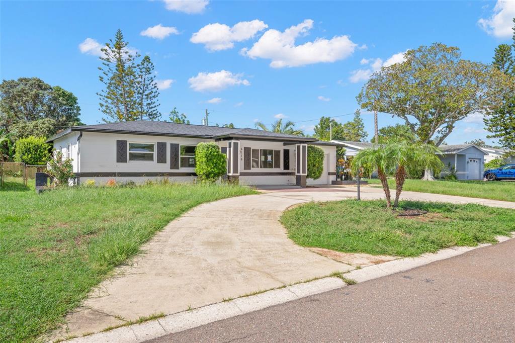 A bright kitchen features white cabinets, a central island, and wood-look flooring — 6116 52ND AVENUE N, KENNETH CITY, FL