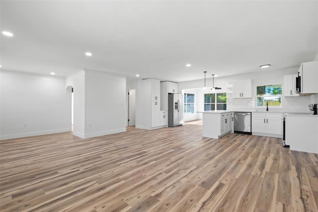 A modern kitchen features white cabinets, stainless steel appliances, a peninsula, and wood-look flooring — 6116 52ND AVENUE N, KENNETH CITY, FL