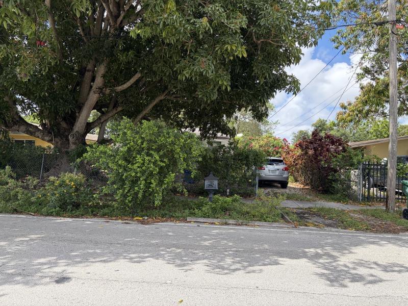 A silver SUV is parked in the driveway of a house shaded by a large tree — 2021 NW 87th Street, Miami FL 33147, MIAMI, FL