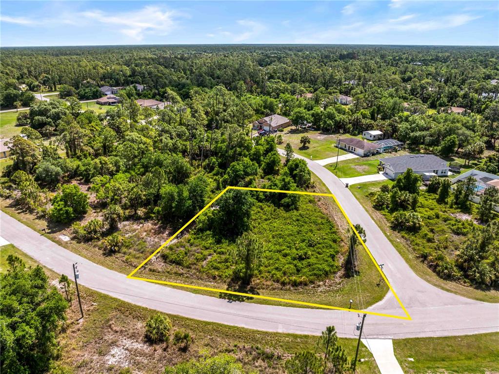An aerial view shows a vacant, trapezoidal-shaped lot bordered by two paved roads — 0 BARCELONA DRIVE Lot 1, NORTH PORT, FL