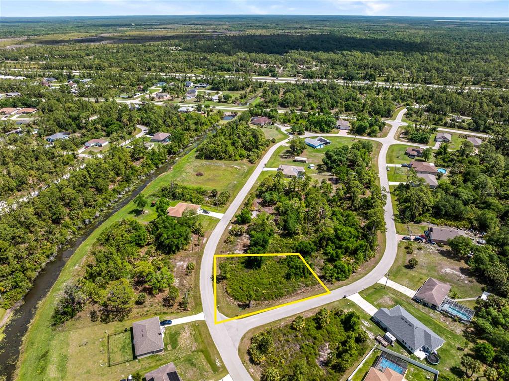 An aerial view shows a vacant, rectangular residential lot outlined in yellow within a suburban neighborhood — 0 BARCELONA DRIVE Lot 1, NORTH PORT, FL
