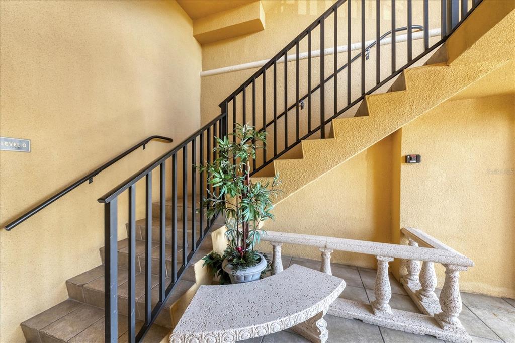 A staircase with black metal railings leads upward in a room with yellow textured walls — 97 VIVANTE BOULEVARD UNIT 204, PUNTA GORDA, FL