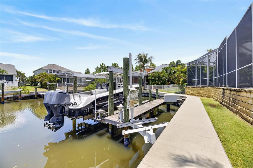 A boat is docked at a private lift along a canal next to a screened enclosure — 508 ISLEBAY DRIVE, APOLLO BEACH, FL