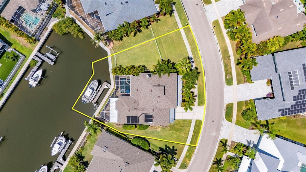 An aerial view shows a waterfront house with a boat dock and a yellow boundary line — 508 ISLEBAY DRIVE, APOLLO BEACH, FL
