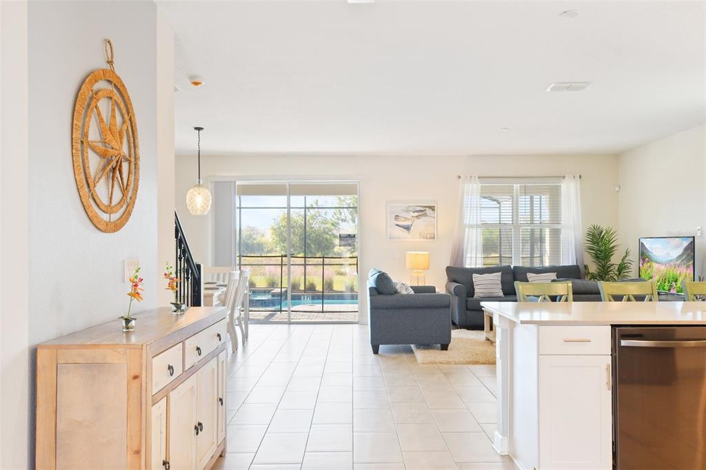 A bright open-concept living area features a kitchen island, dining space, and sliding glass doors — 2874 STANZA CT, KISSIMMEE, FL