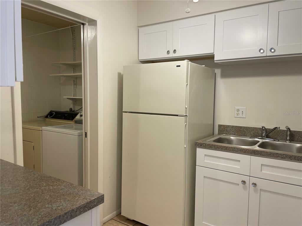 A kitchen features white cabinets, a white refrigerator, a double sink, and an adjacent laundry area — 3952 ELVIRA COURT, NEW PORT RICHEY, FL