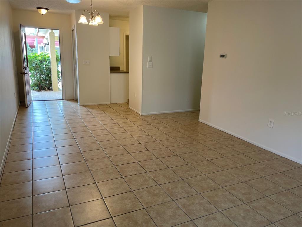 An interior view shows a tiled living area leading to an open kitchen and exterior door — 3952 ELVIRA COURT, NEW PORT RICHEY, FL