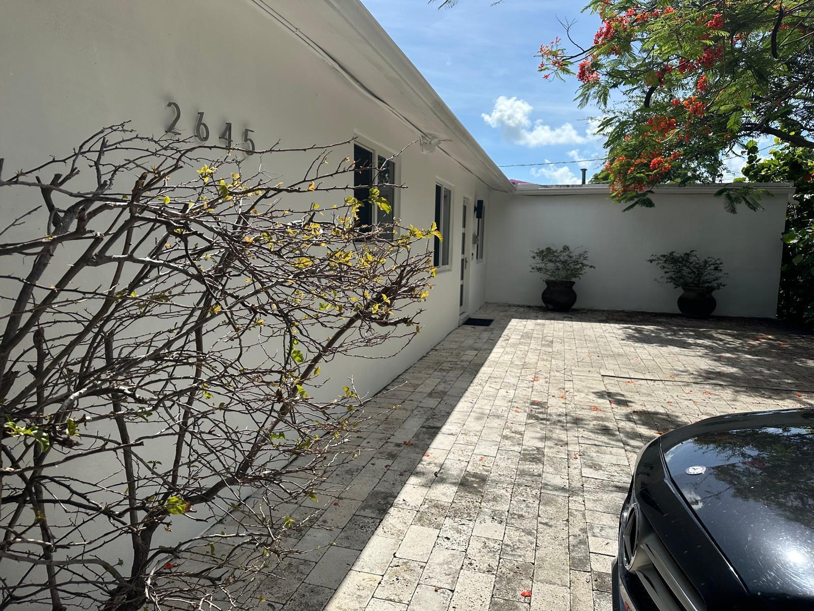 A white exterior wall with house numbers, a paved driveway, and a flowering tree — 2645 Scott Street, Hollywood FL 33020, HOLLYWOOD, FL