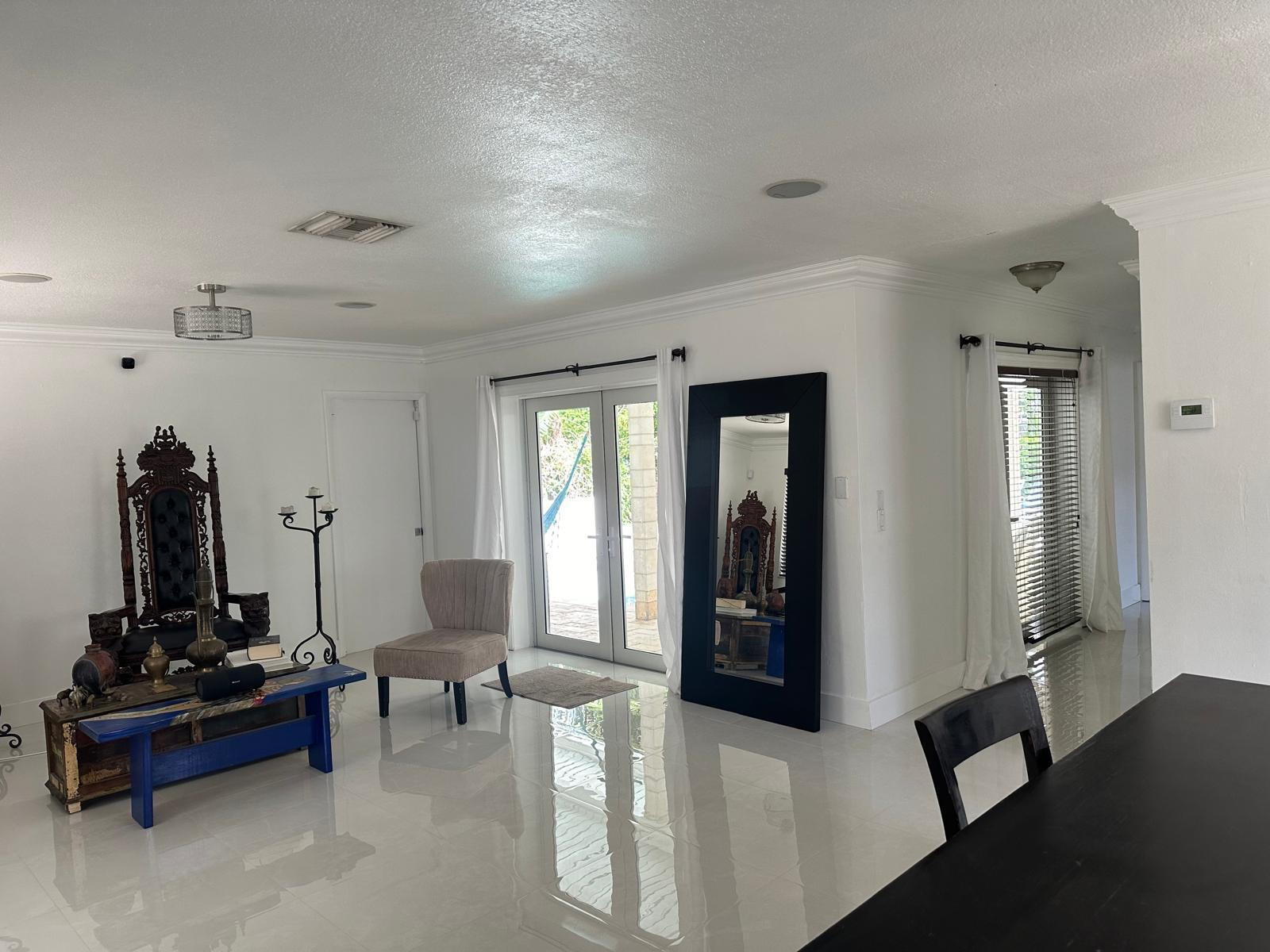 A bright living room features white tile floors, a large ornate chair, and glass doors — 2645 Scott Street, Hollywood FL 33020, HOLLYWOOD, FL