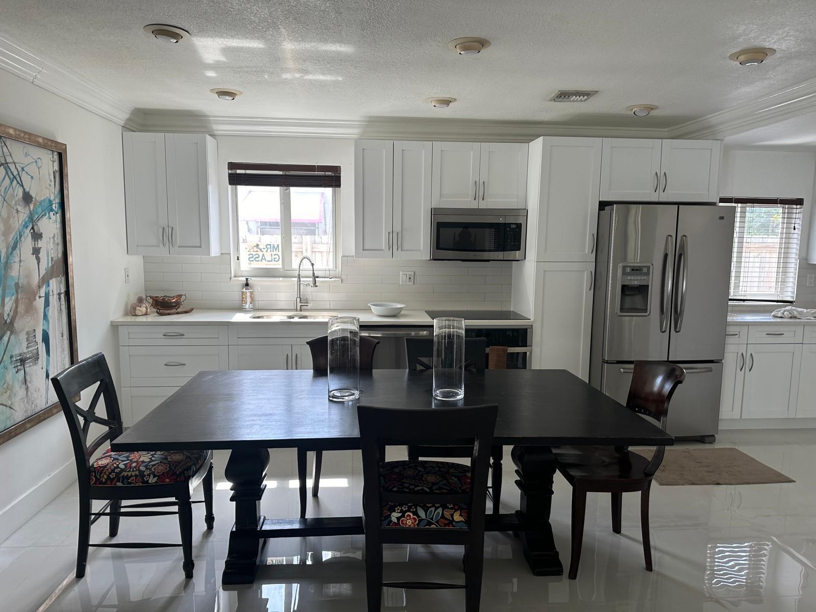 A kitchen with white cabinets, stainless steel appliances, and a dark wooden dining table — 2645 Scott Street, Hollywood FL 33020, HOLLYWOOD, FL