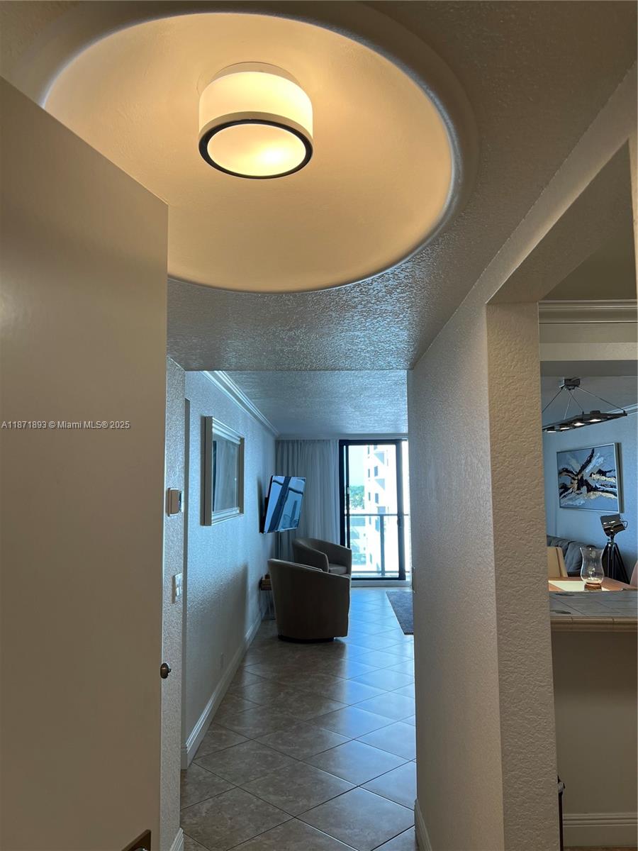 A hallway with tile flooring leads to a living area featuring a balcony and chairs — 2301 S Ocean Dr # 506, Hollywood FL 33019, HOLLYWOOD, FL