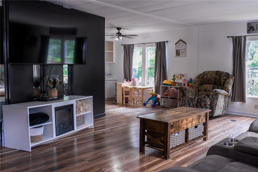 A living room features dark wood flooring, a large wall-mounted television, and a fireplace console — 5843 NE 167TH AVENUE, SILVER SPRINGS, FL