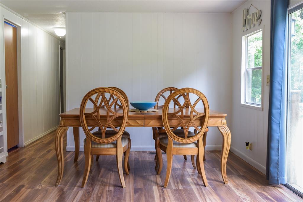 A dining room features a wooden table with four circular-back chairs on wood-look flooring — 5843 NE 167TH AVENUE, SILVER SPRINGS, FL