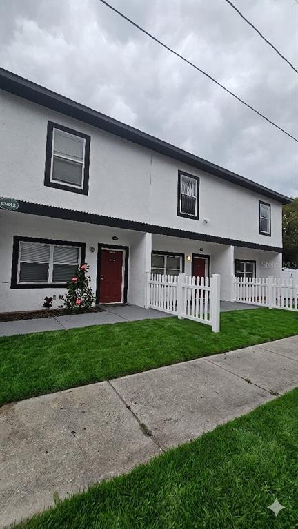 A two-story white townhouse exterior features red front doors and a white picket fence — 13612 N 21ST STREET, TAMPA, FL