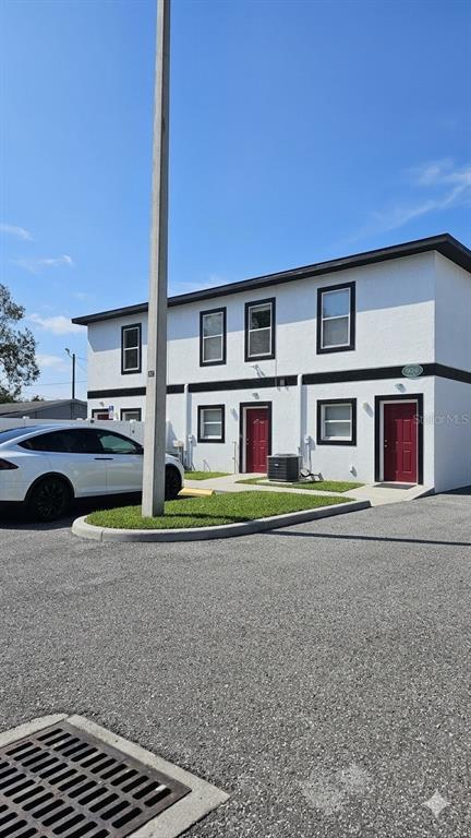 A two-story white apartment building with red doors and a white car parked outside — 13612 N 21ST STREET, TAMPA, FL