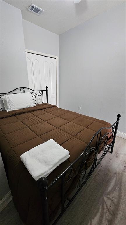 A bedroom features a metal bed frame with a brown comforter and a white towel — 13612 N 21ST STREET, TAMPA, FL