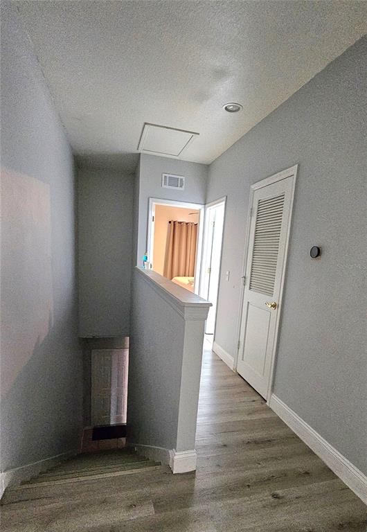 A hallway with light wood-look flooring leads to two doorways and a staircase landing — 13612 N 21ST STREET, TAMPA, FL