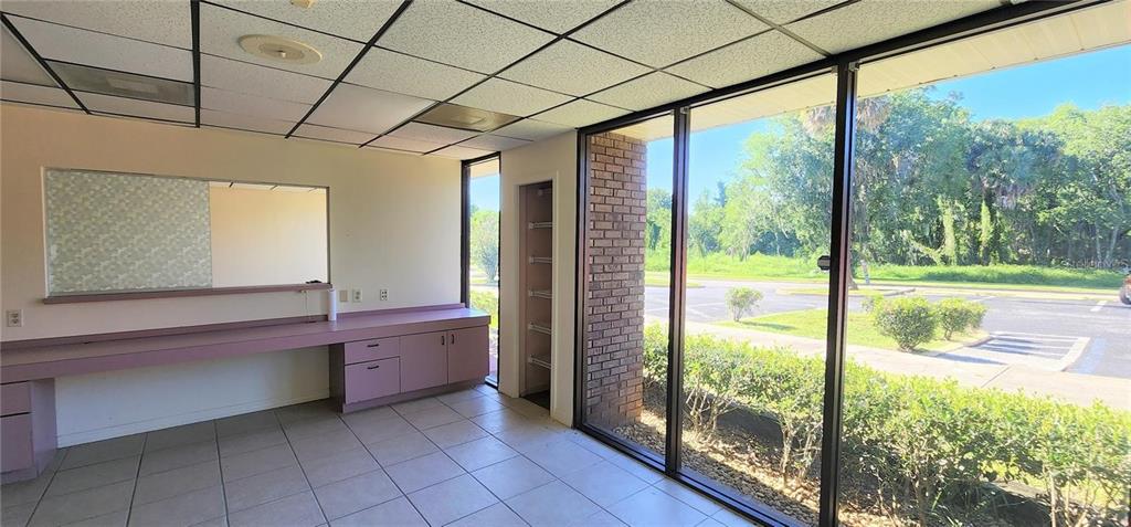 An office space with a built-in mauve desk, tiled floors, drop ceiling, and large windows — 150 SE 17TH STREET UNIT 603, OCALA, FL