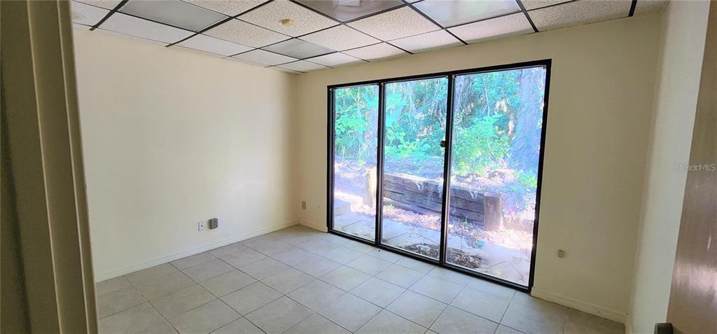 An empty room features light-colored tile flooring, a drop ceiling, and large sliding glass doors — 150 SE 17TH STREET UNIT 603, OCALA, FL