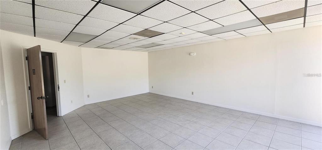 An empty office room features white walls, a drop ceiling, and light-colored tiled flooring — 150 SE 17TH STREET UNIT 603, OCALA, FL