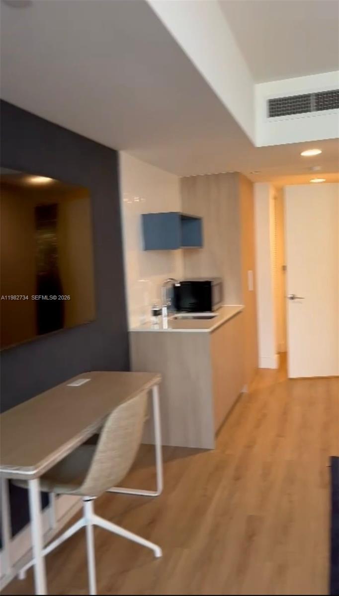 A small kitchenette with light wood cabinets and a desk area in a modern room — 159 NE 6th St # 1804, Miami FL 33132, MIAMI, FL