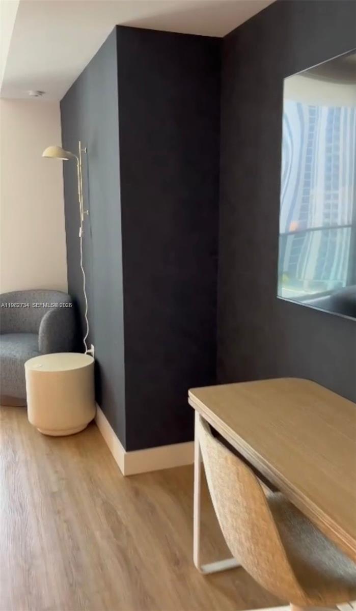 A modern room features a dark accent wall, a light wood desk, and a wall lamp — 159 NE 6th St # 1804, Miami FL 33132, MIAMI, FL