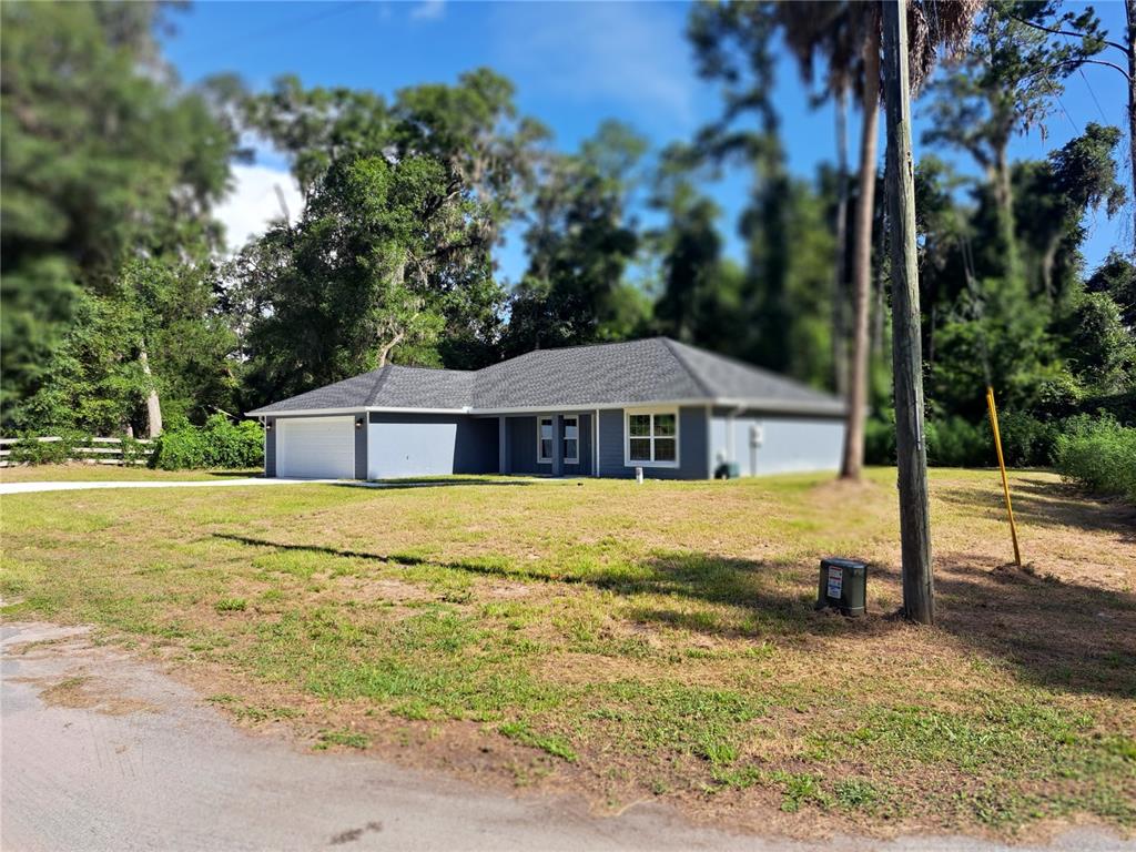 A single-story gray house with a white garage door sits on a grassy lot — 547 GRAPEWOOD LN., CITRUS SPRINGS, FL