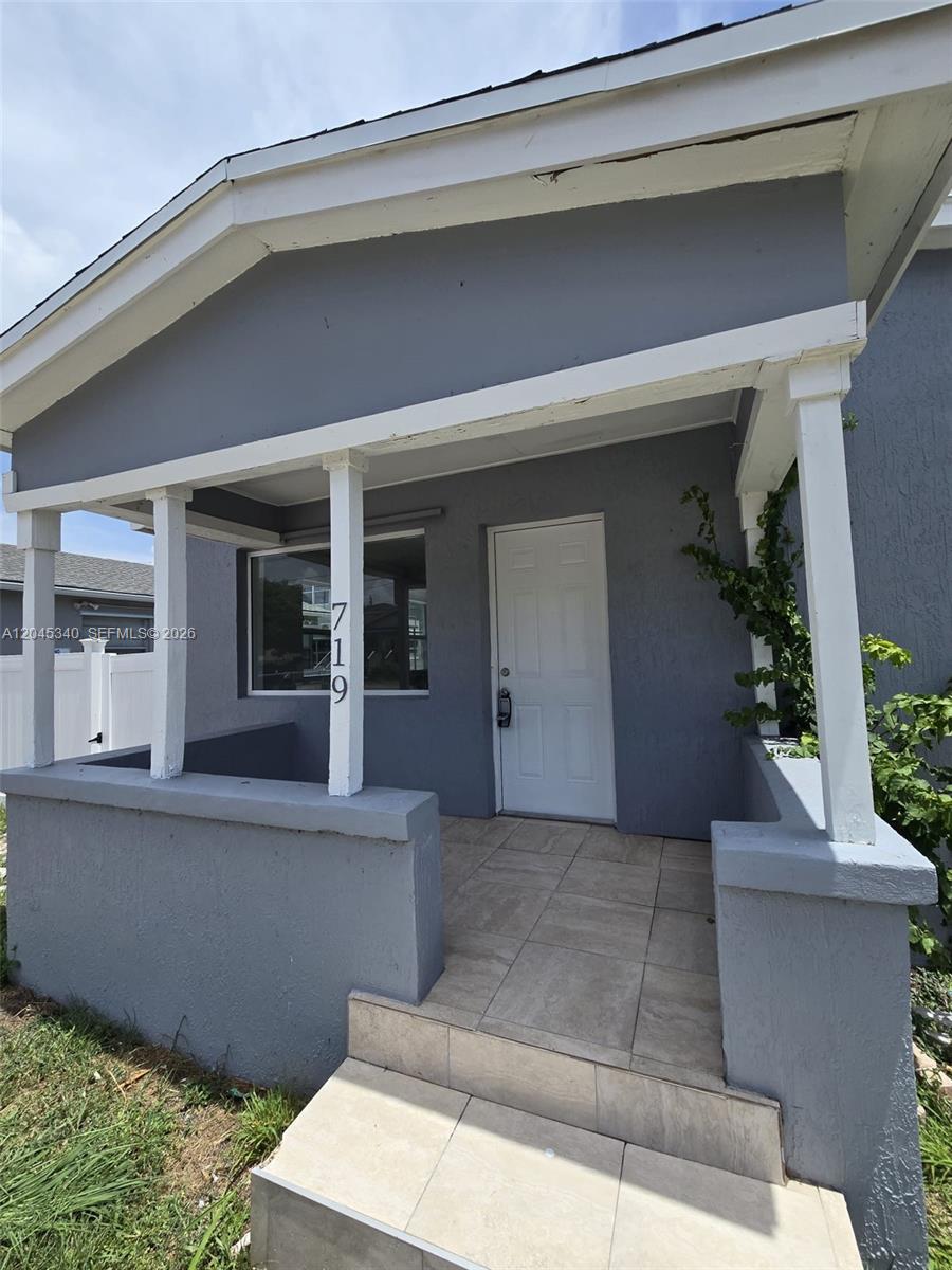 The exterior of a gray house features a covered front porch with tiled steps — 719 21st St, West Palm Beach FL 33407, WEST PALM BEACH, FL